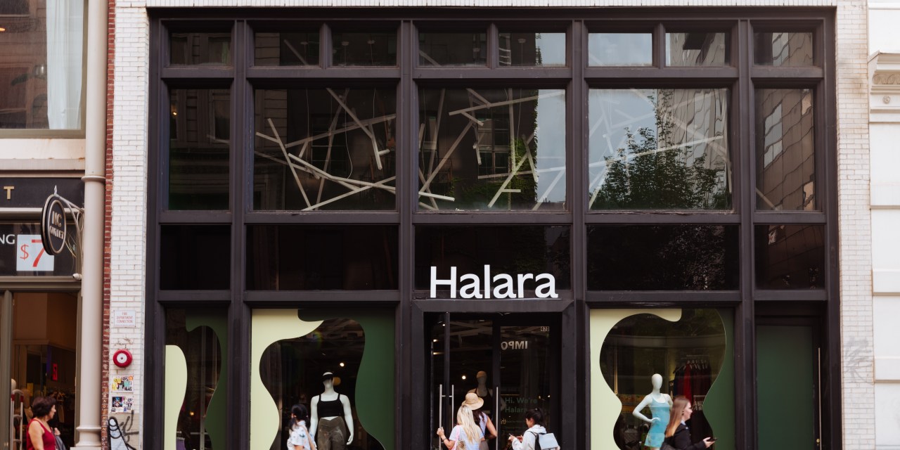 Photo of a store entrance with a sign that says Halara as pedestrians walk by on a busy sidewalk.